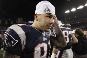 FILE - In this Sunday, Jan. 22, 2012, file photo, New England Patriots tight end Aaron Hernandez puts on a Super Bowl cap following the AFC Championship NFL football game against the Baltimore Ravens in Foxborough, Mass. Hernandez, who was serving a life sentence for a murder conviction and just days ago was acquitted of a double murder, died after hanging himself in his prison cell Wednesday, April 19, 2017, Massachusetts prisons officials said. (AP Photo/Winslow Townson, File)